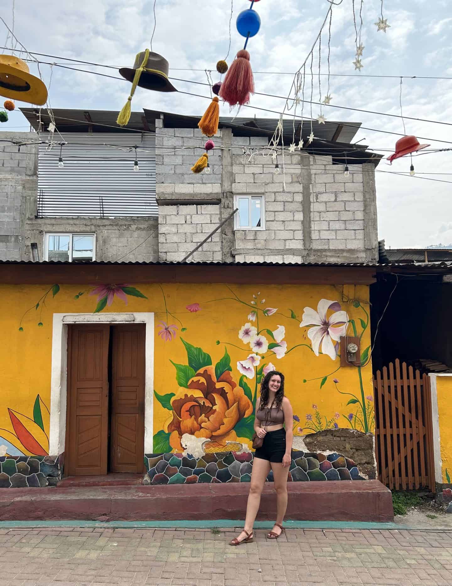 girl standing in front of building with yellow flower mural