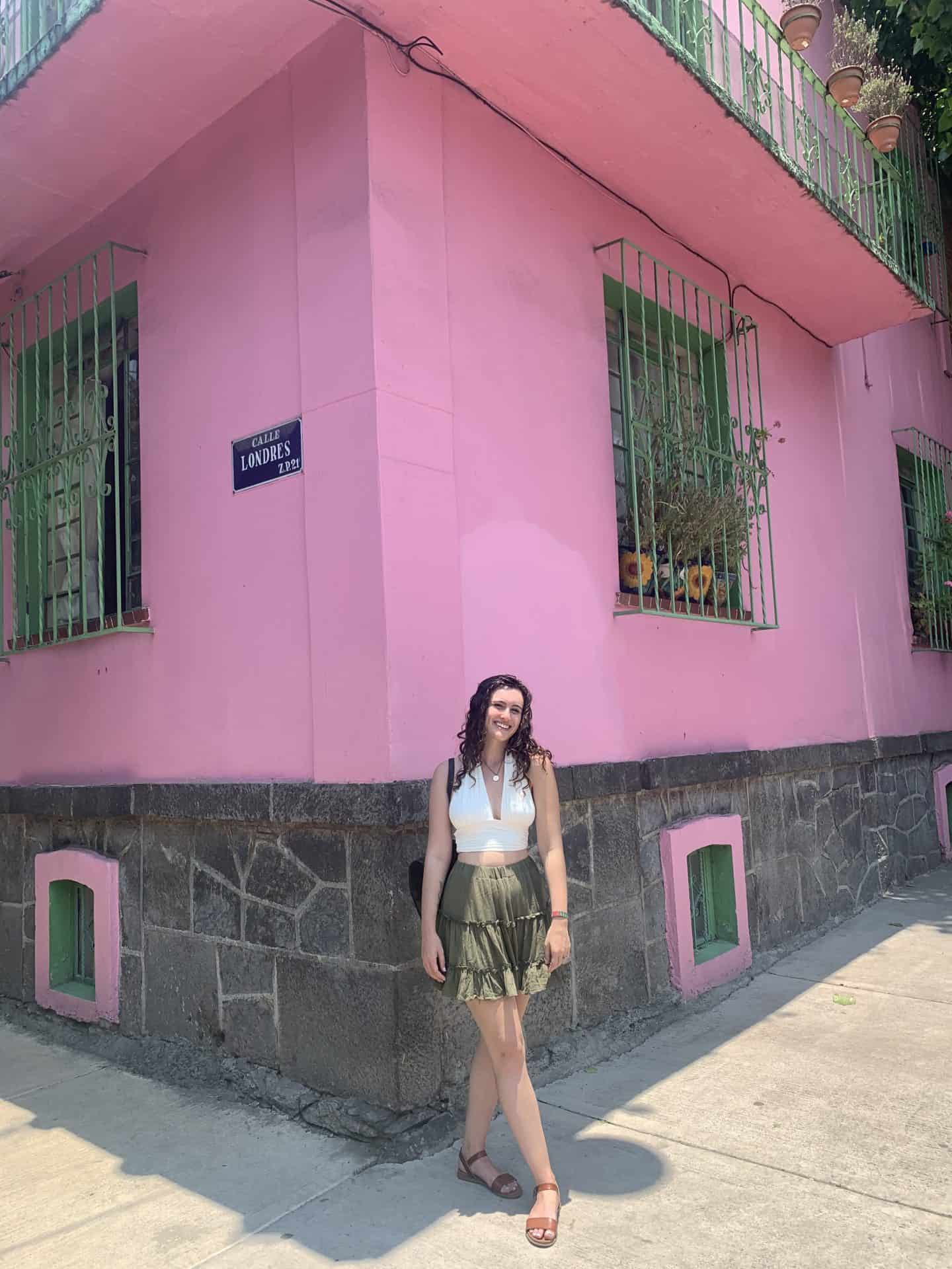 A woman standing in front of pink building in Mexico City