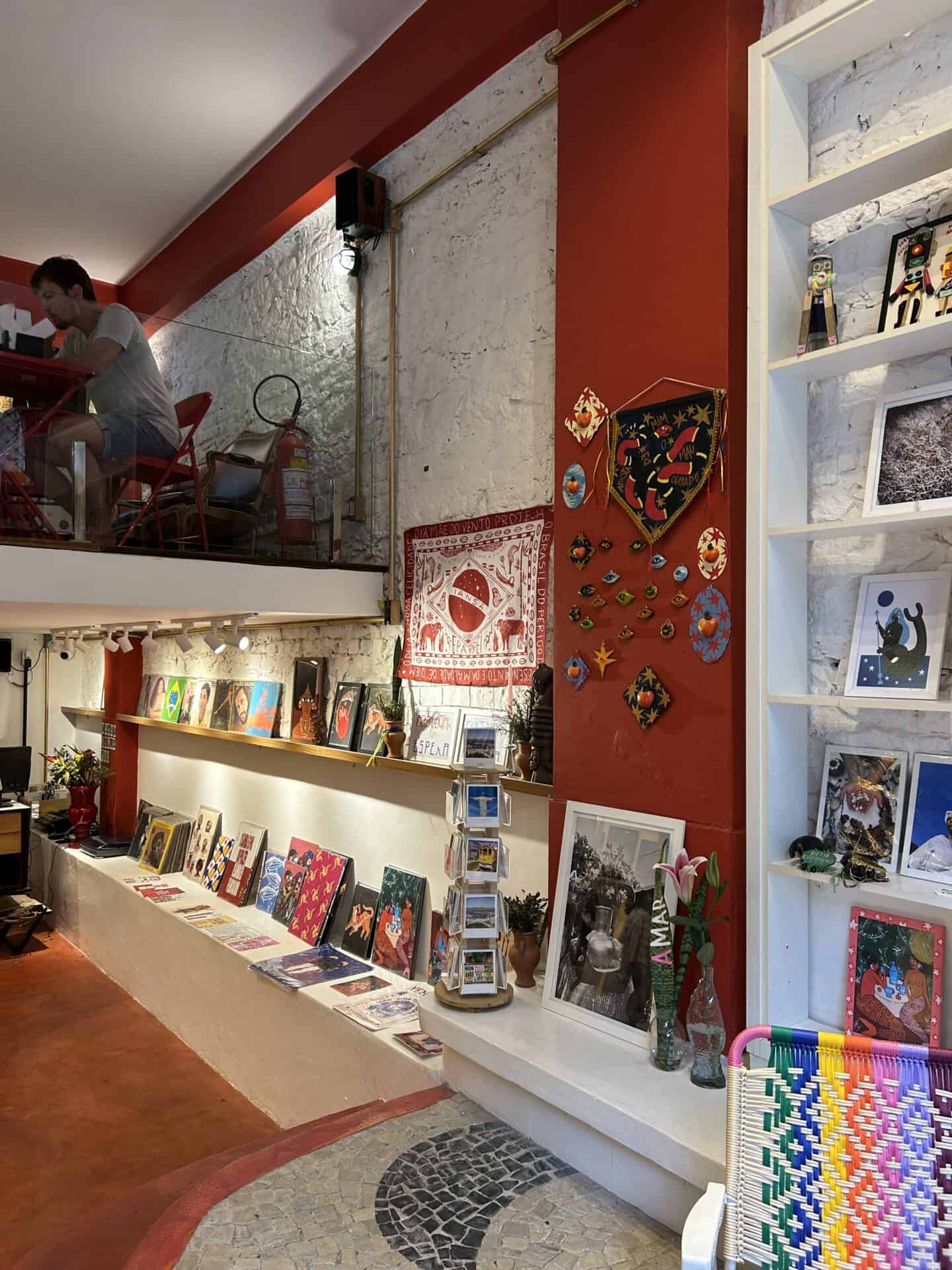 A shop inside Santa Teresa, Rio de Janeiro, Walls are red and white, and artwork is displayed.