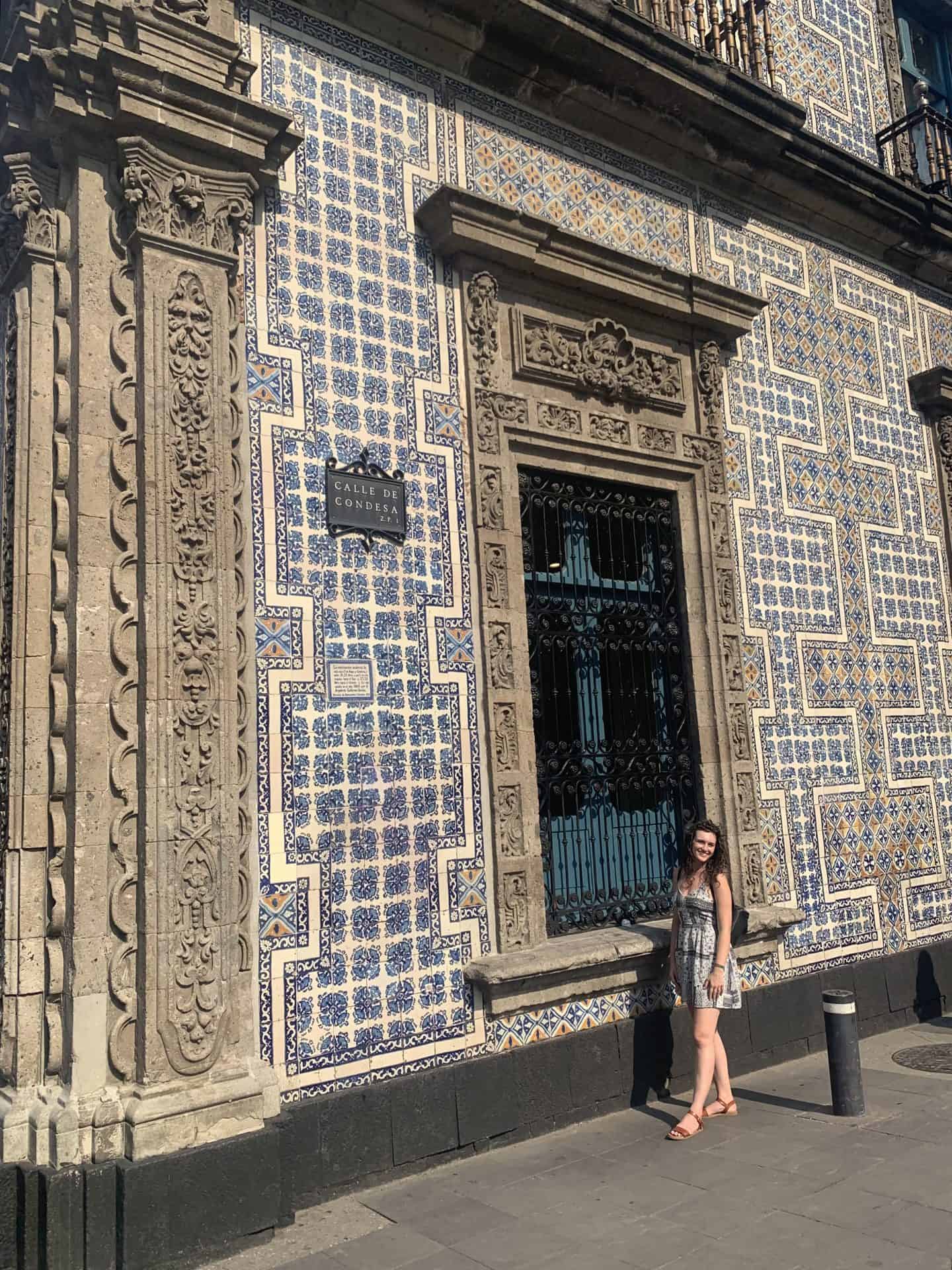 Girl standing in front of blue and white tiled building in Mexico City