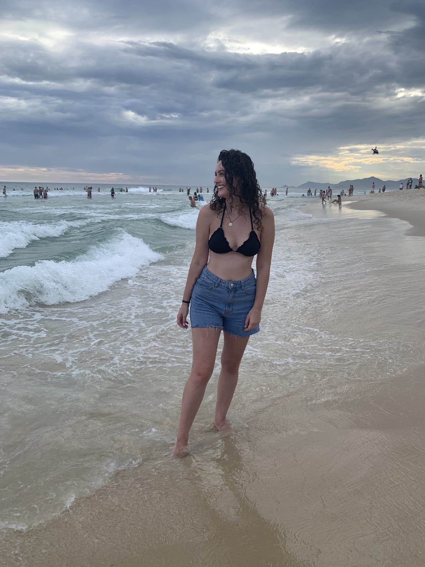 A girl wearing a bathing suit top and shorts on the beach, in Barra da Tijuca, two essentials you don't want to forget to pack when visiting Rio de Janeiro.