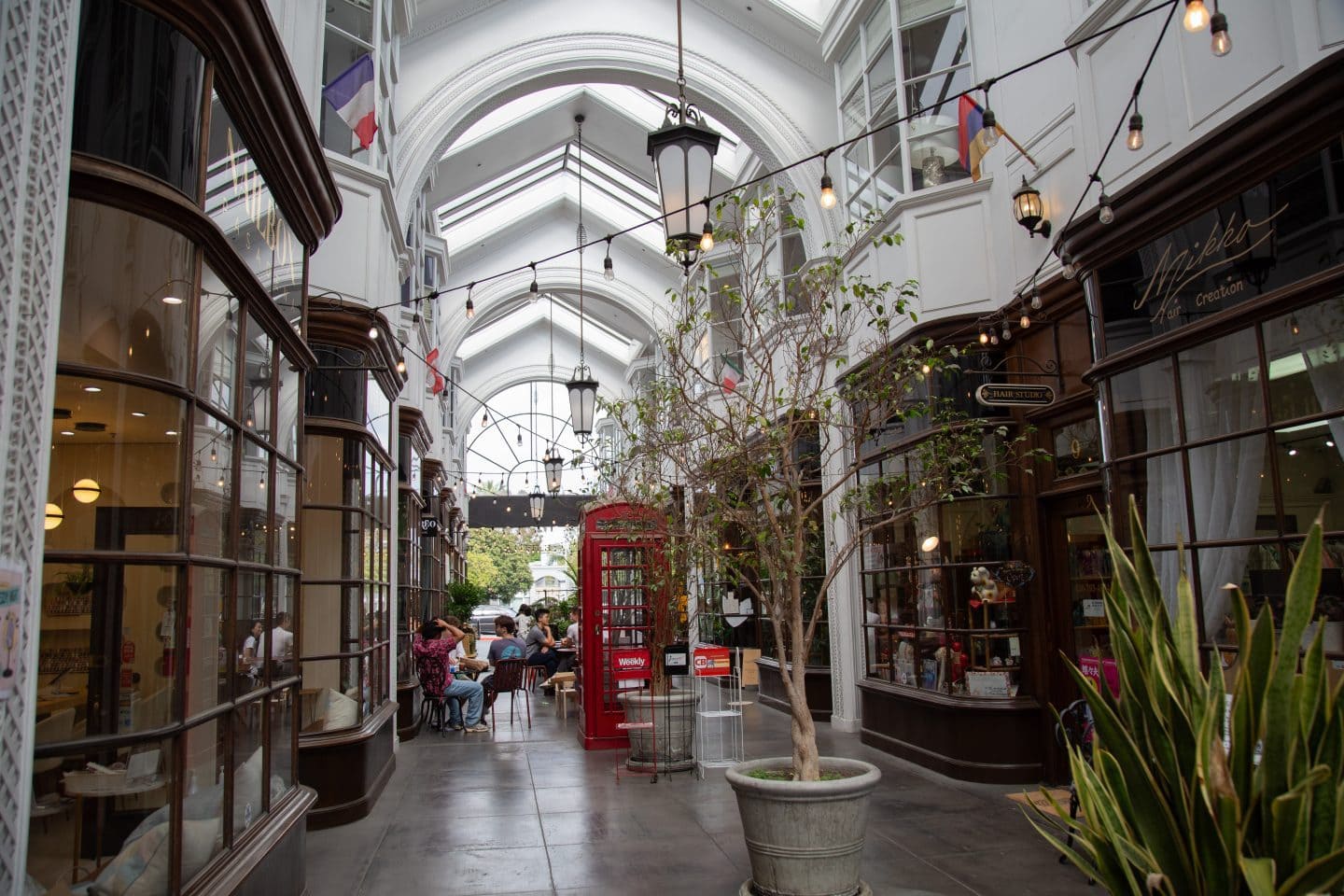Burlington Arcade, a UK-inspired shopping corridor in Pasadena. There are a number of shops, with flags on the ceiling, and a red telephone booth at the center of the photo.