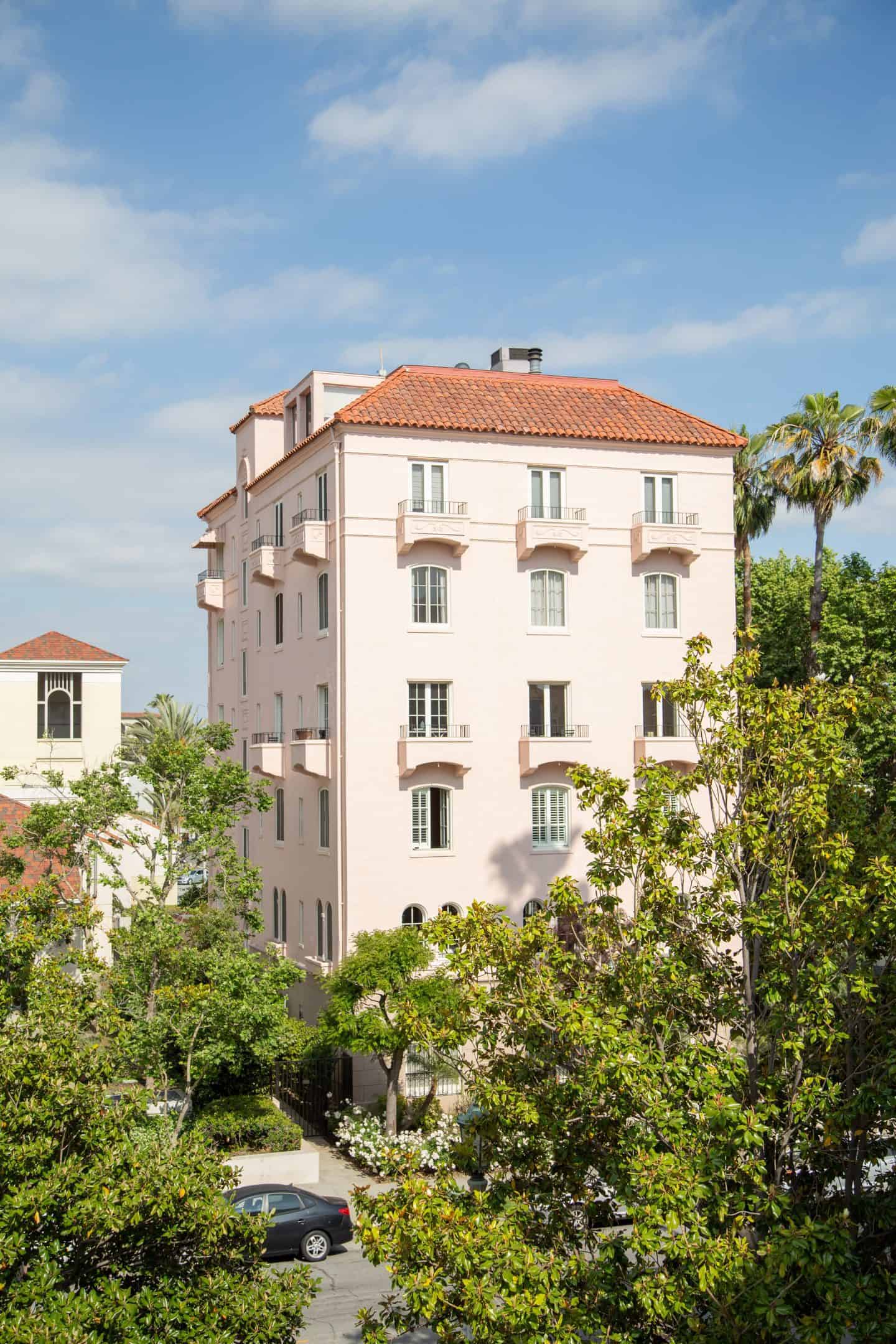 A tall pink apartment building, surrounded by greenery in Pasadena, California.