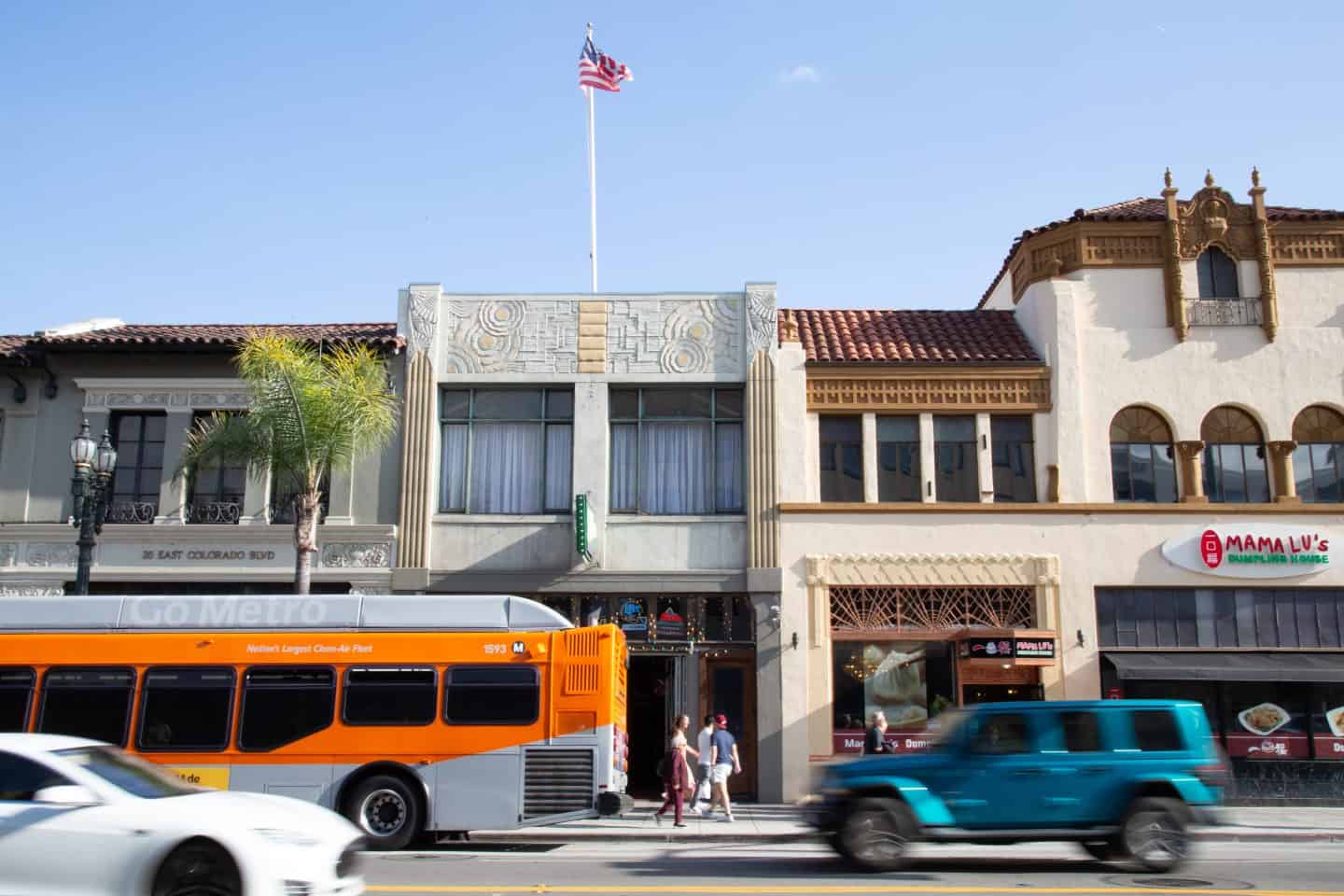 A bus, cars, and people move in front of buildings in Pasadena - they are all out of focus.