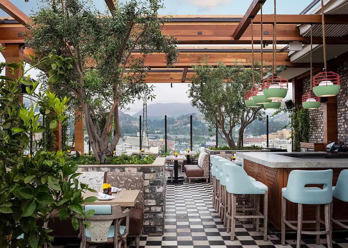 Rooftop restaurant with plants and view of mountains in background at Dream Hollywood Hotel in Los Angeles.