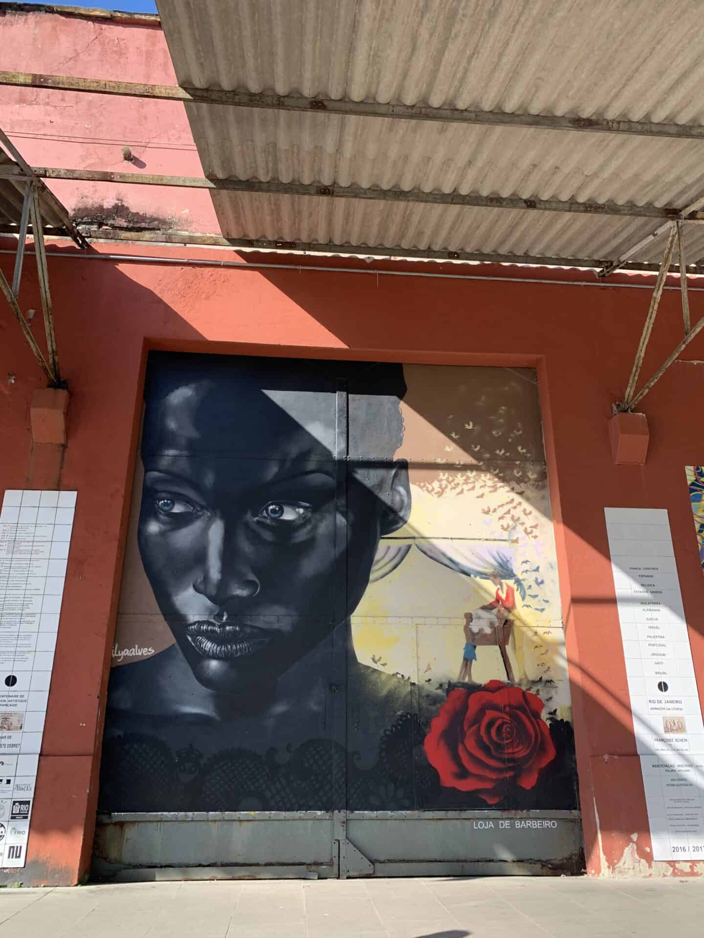 Mural of Black woman with serious expression and white rose in Centro, Rio de Janeiro.