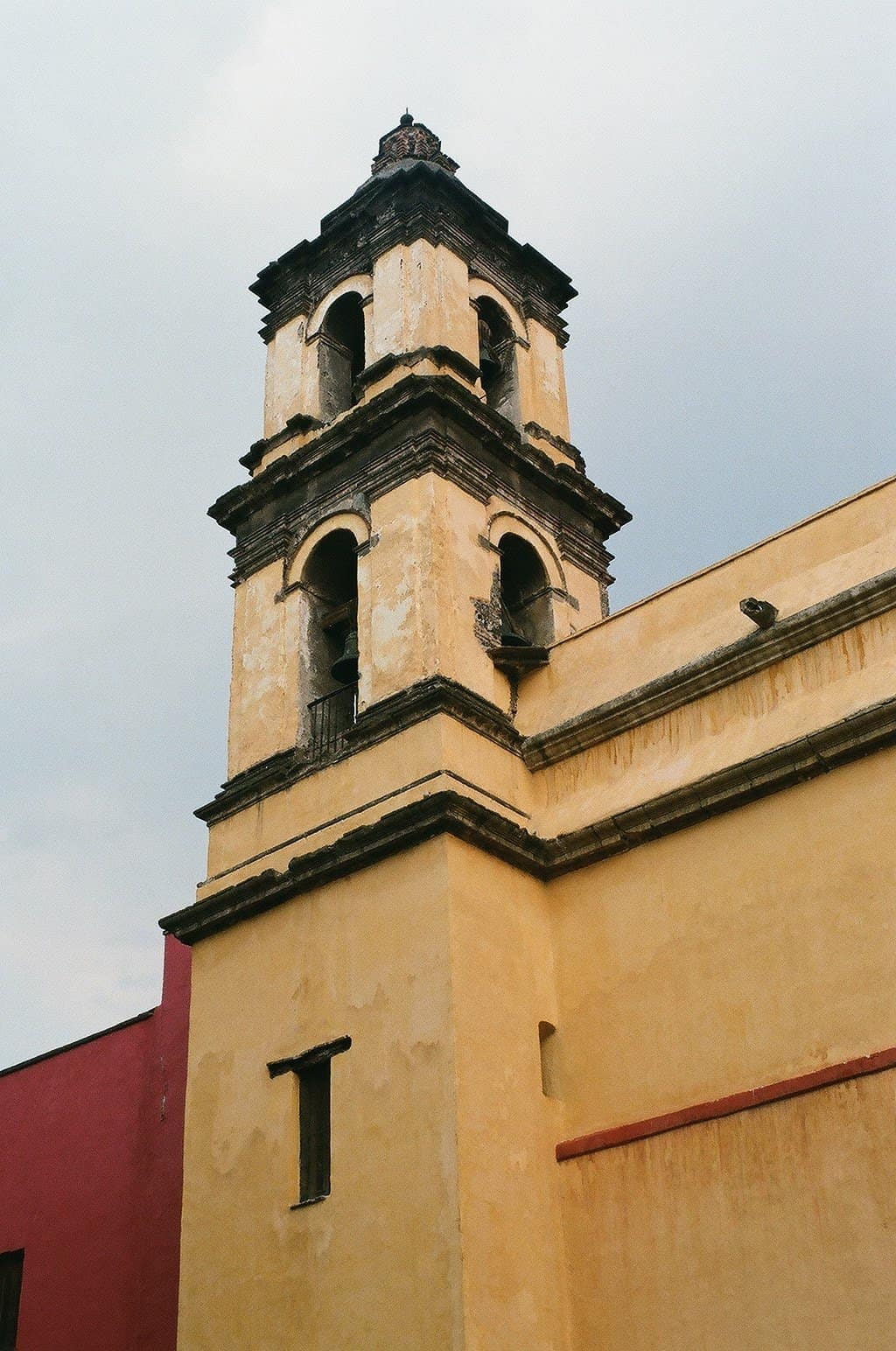A yellow tower of a church in Mexico City