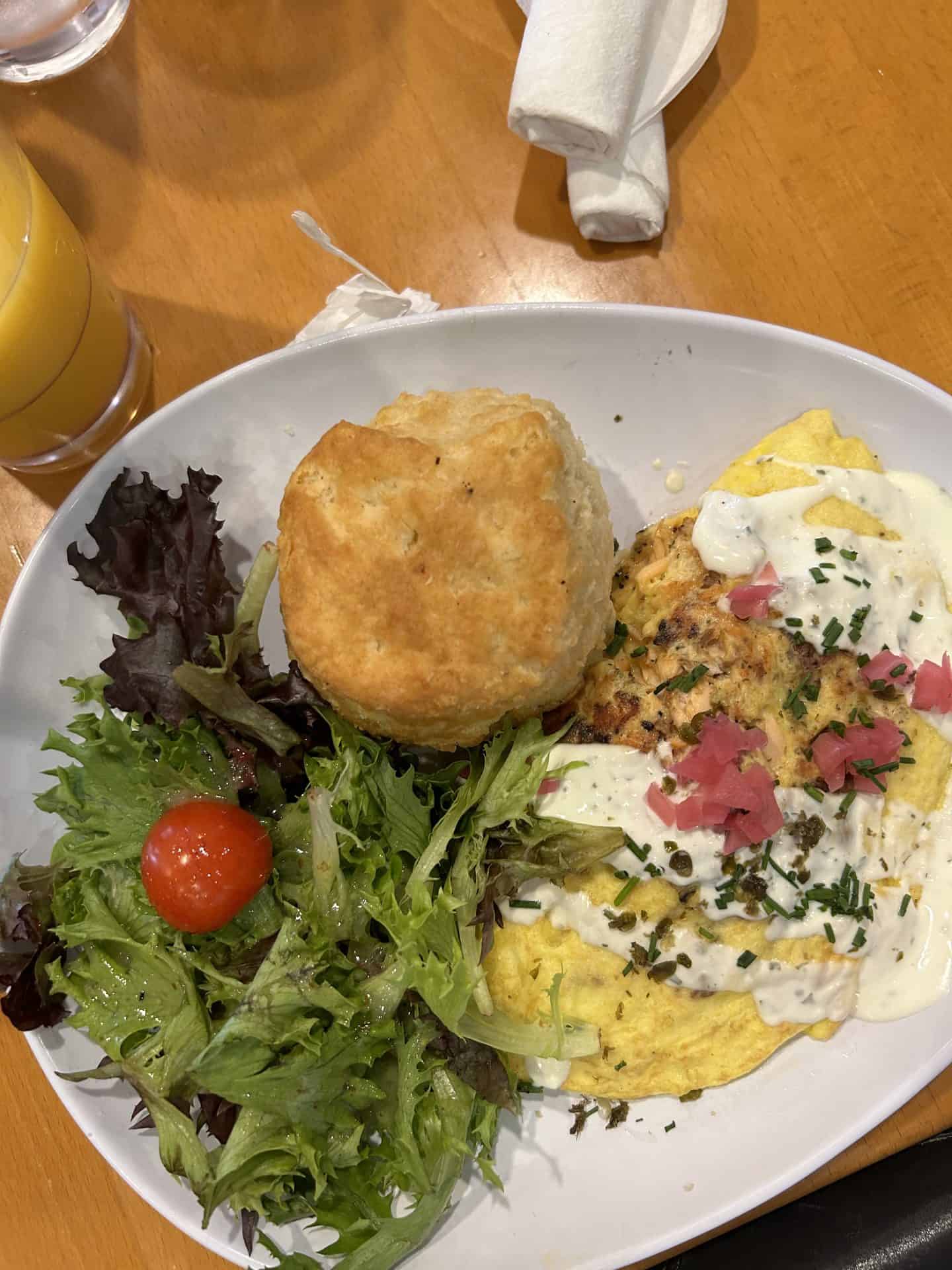 An omelet with a white sauce, a salad, and a biscuit in New Orleans