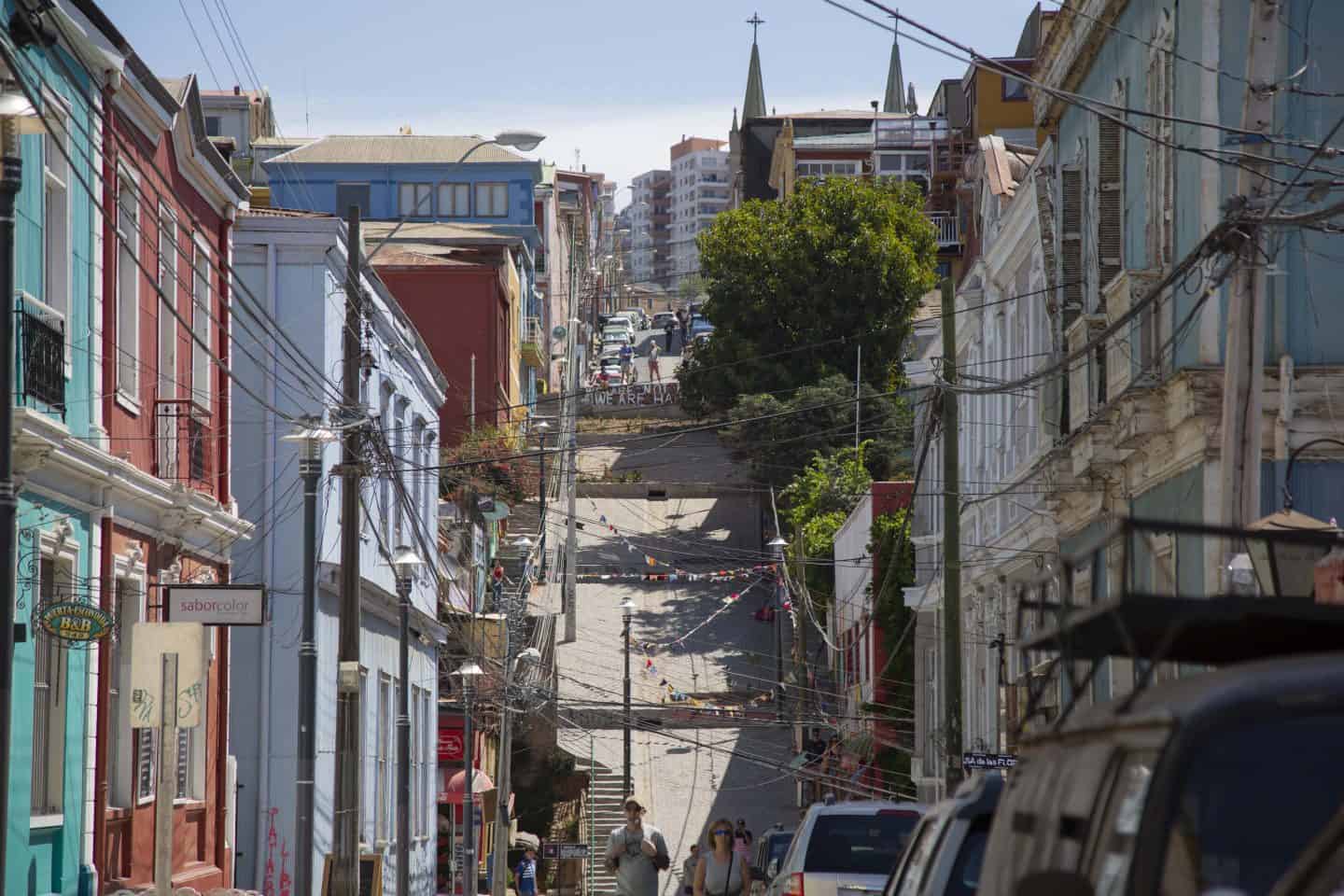a street with a large hill and buildings and people on it in Valparaiso, Chile