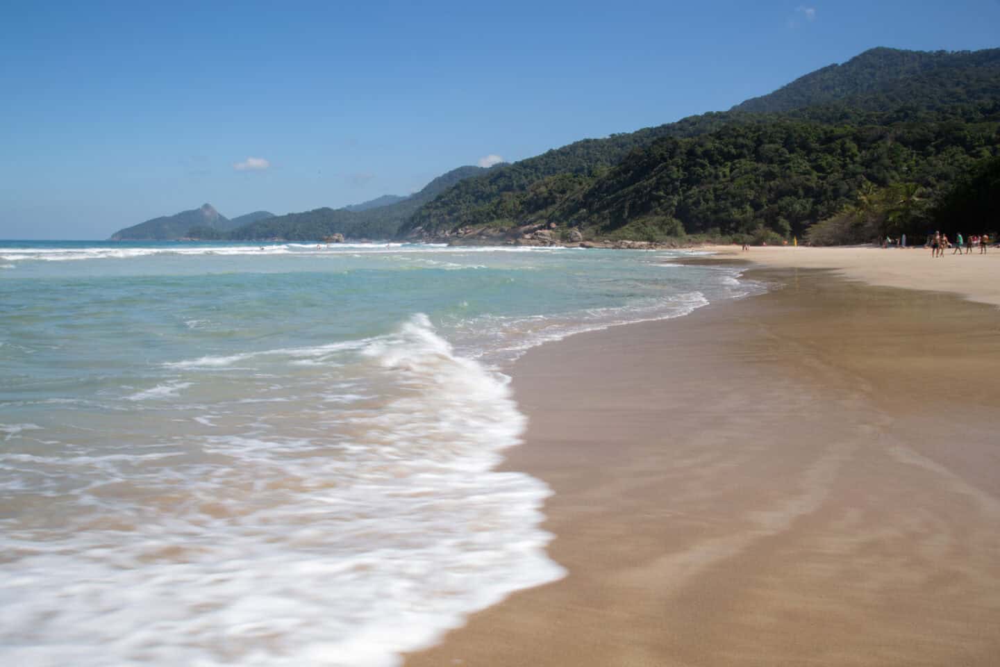 Waves crash into the shore of Praia Lopes Mendes, in Ilha Grande, with mountains in the background.