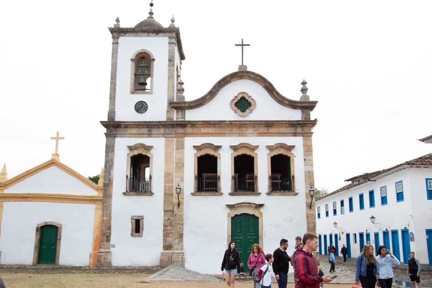 People stand in front of a church in Paraty, Brazil.