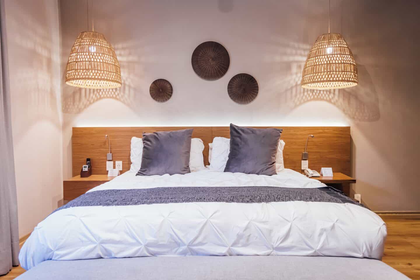 A bed with a wooden headboard, lamps, and wall art at Ágata Hotel Boutique and Spa in Mexico City.