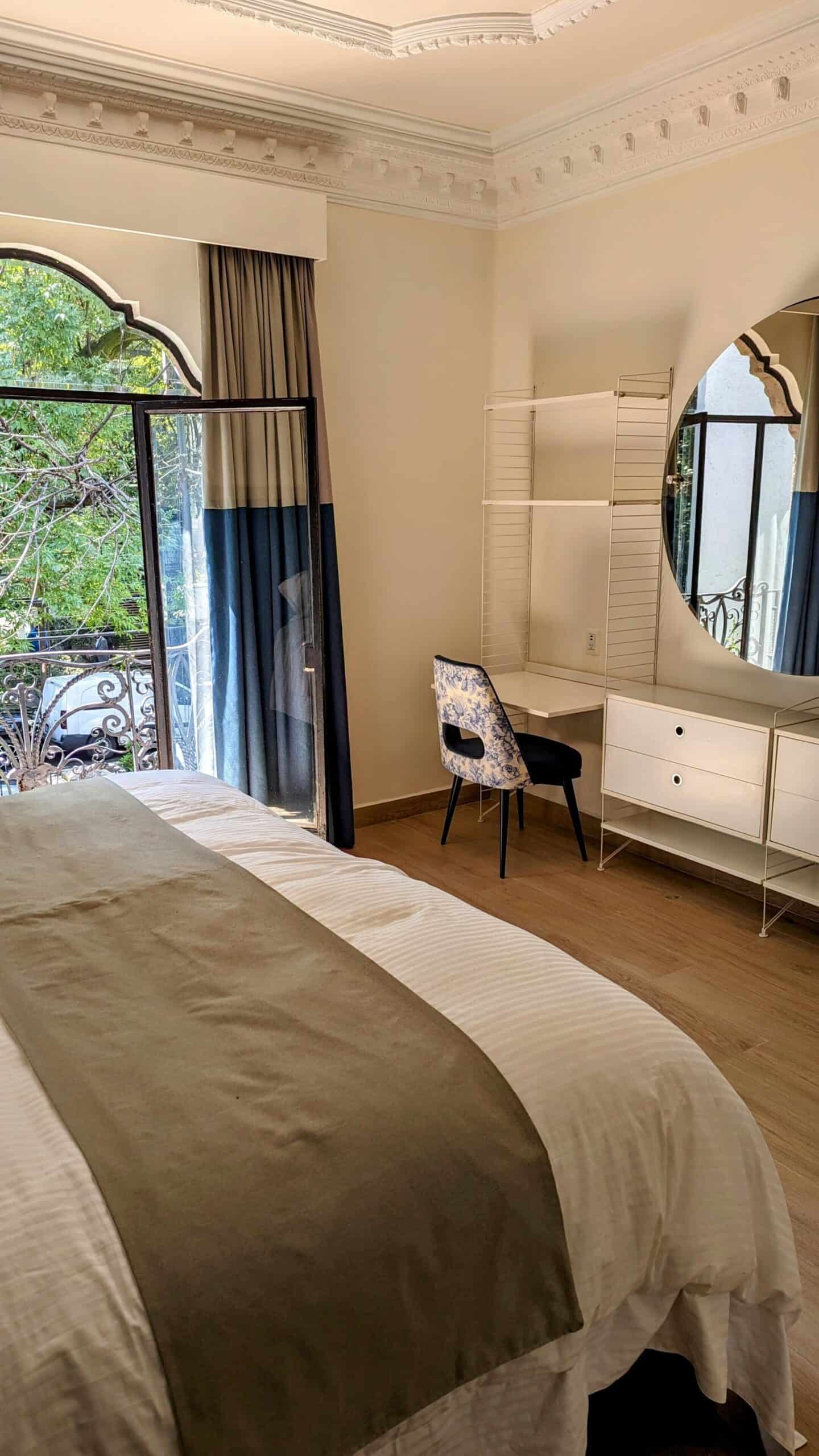 Bed with desk and doors opening to balcony at Casa Amari in Mexico City.