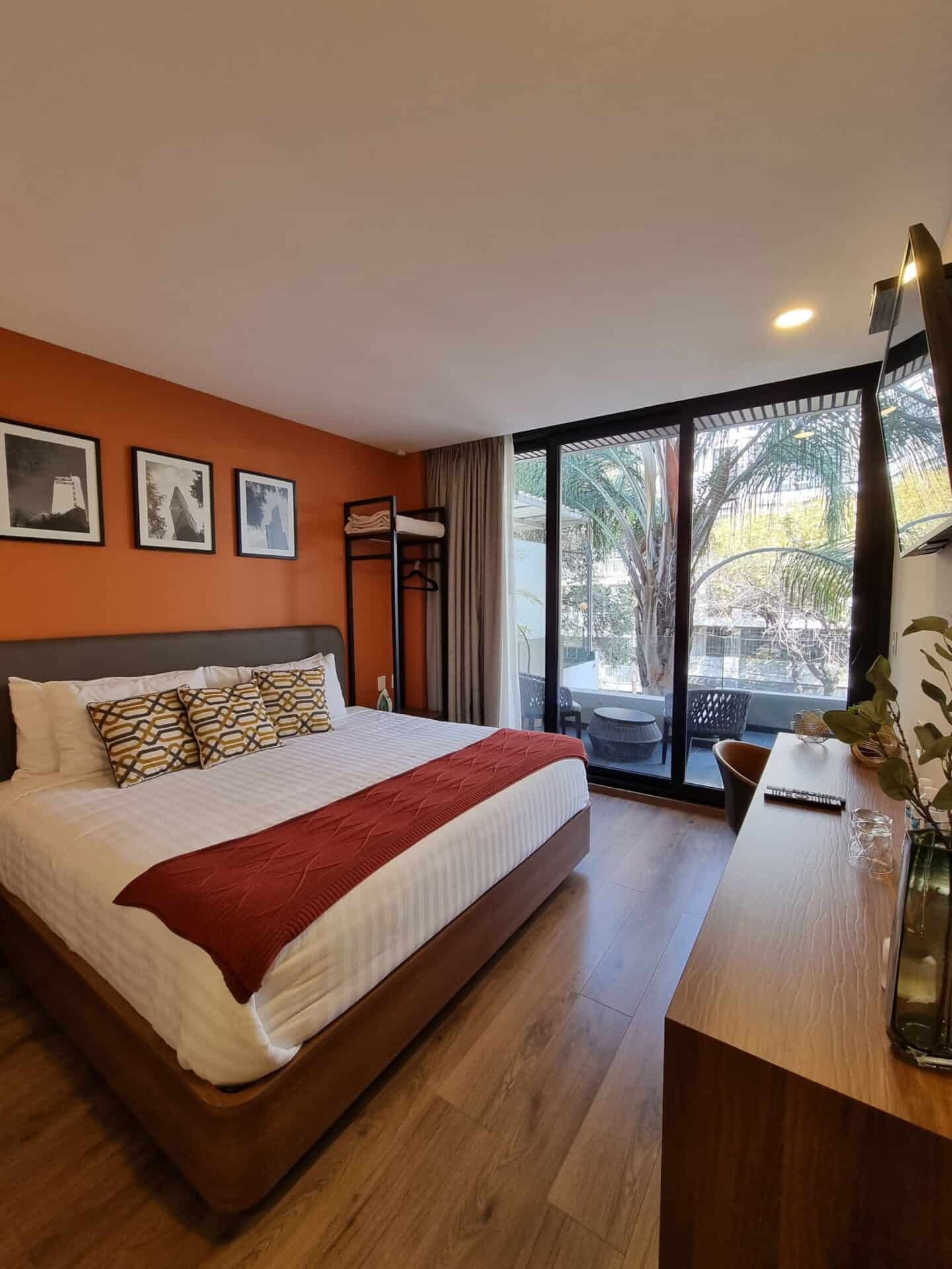 A bedroom with an orange wall and a balcony at Condesa Cibel in Mexico City.