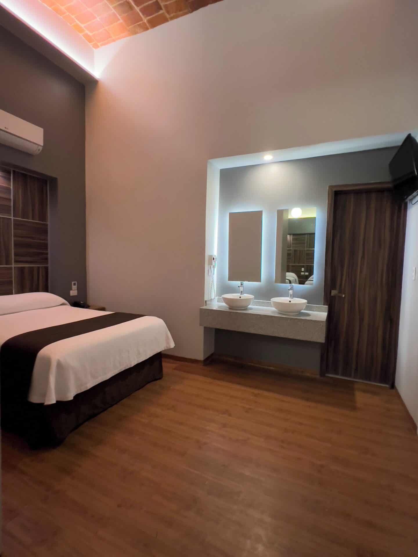Spacious bedroom with two sinks at Hotel Principal in Mexico City.