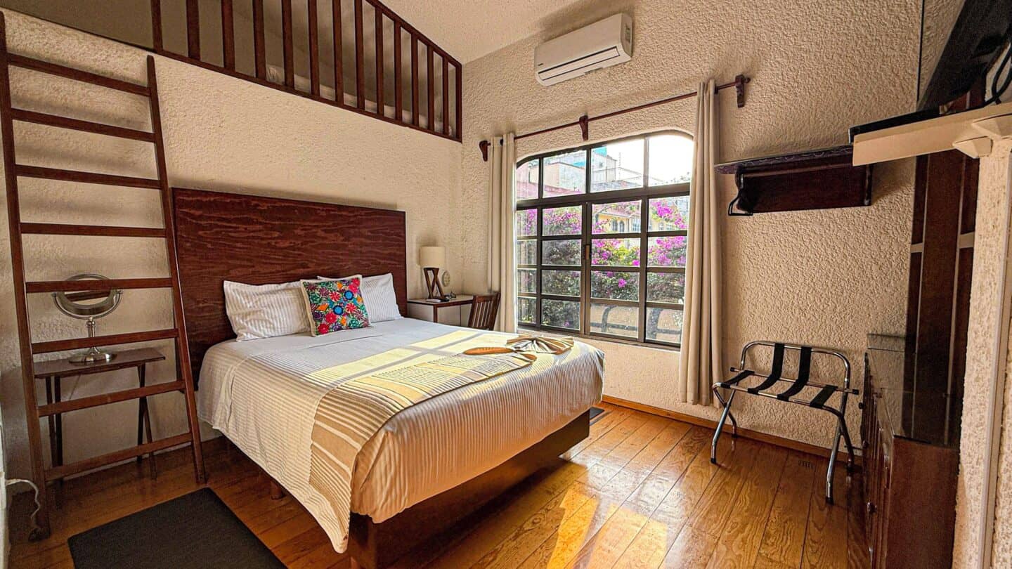 A bedroom with a wooden headboard, and a window at La Casita de Coyoacán in Mexico City.
