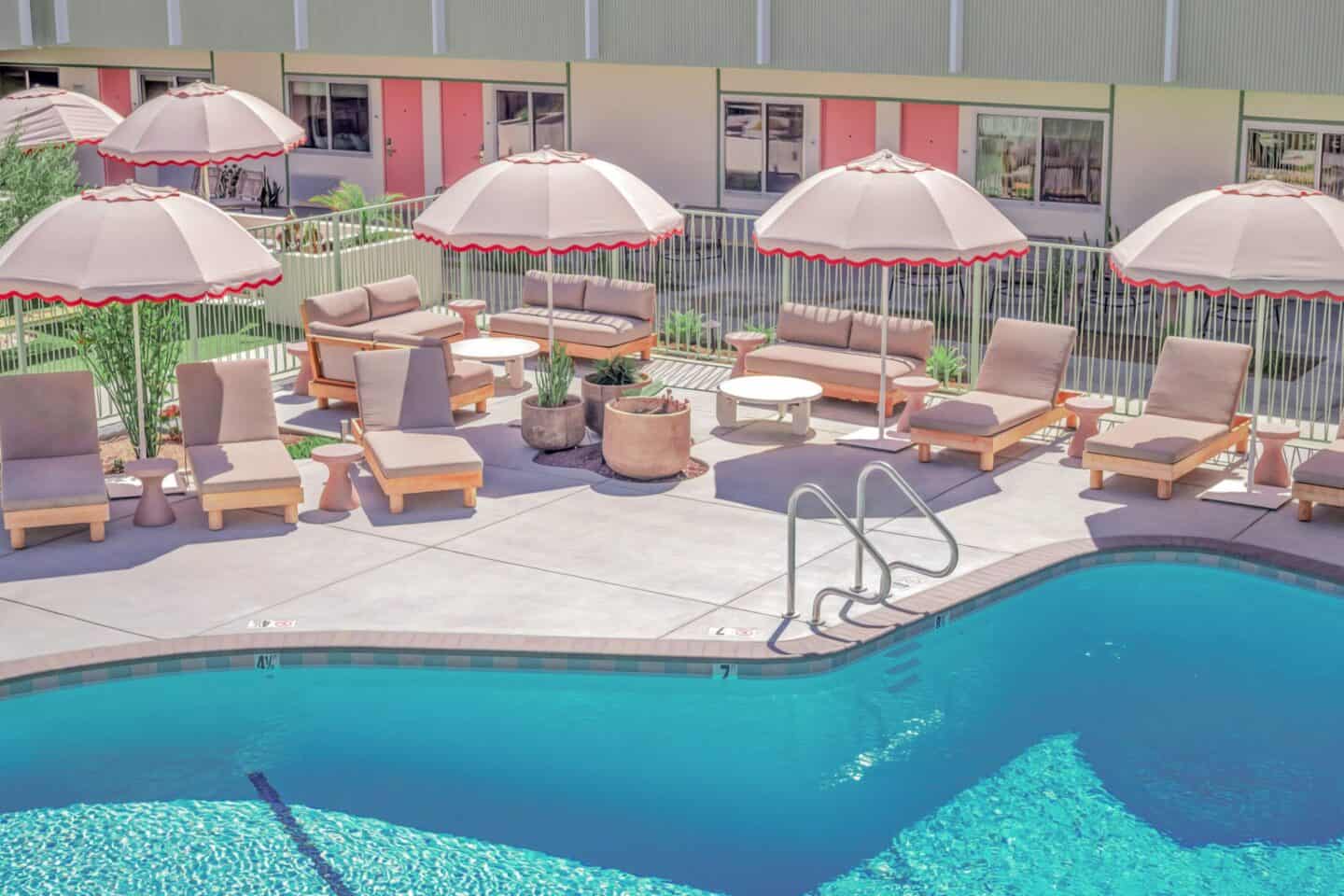 Outdoor pool with lots of seating and pink umbrellas at City Center Hotel in Long Beach, California.