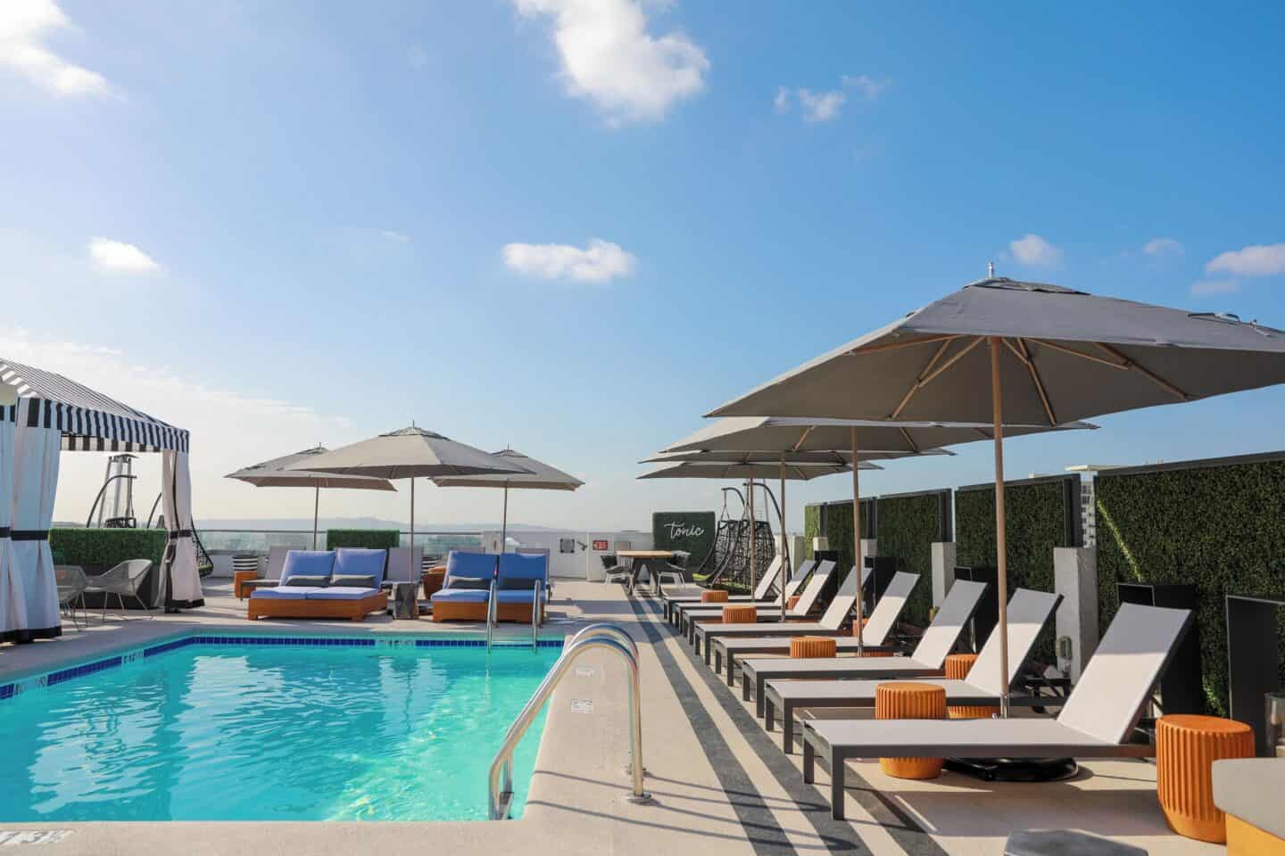 The rooftop pool at Montrose at Beverly Hills in West Hollywood, Los Angeles. Chairs surround the pool with umbrellas.