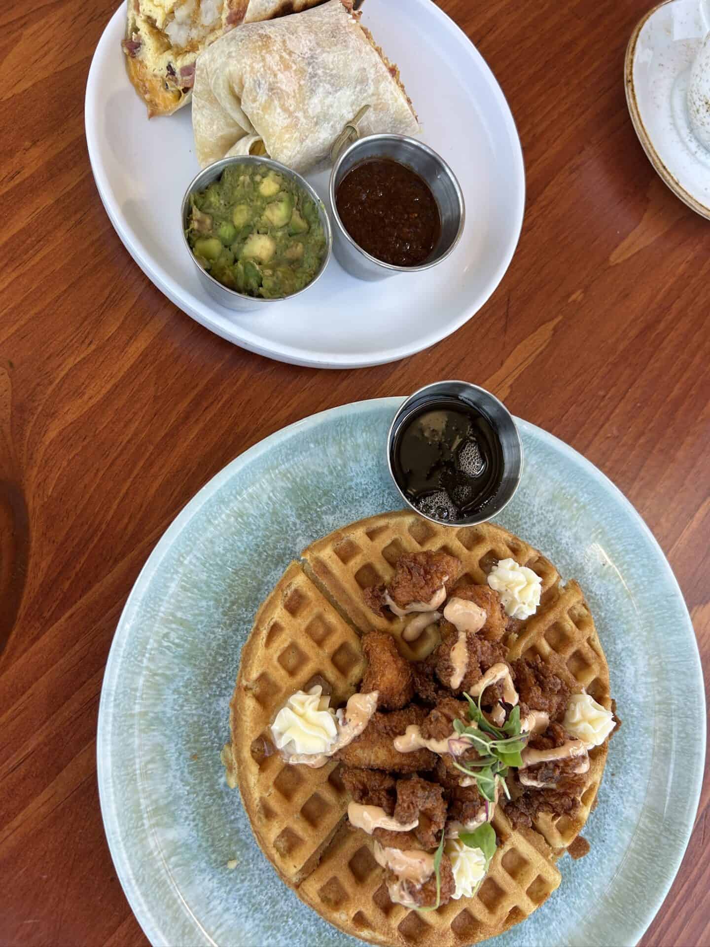 Waffles with fried chicken, whipped cream, and herbs served with Indian dishes.