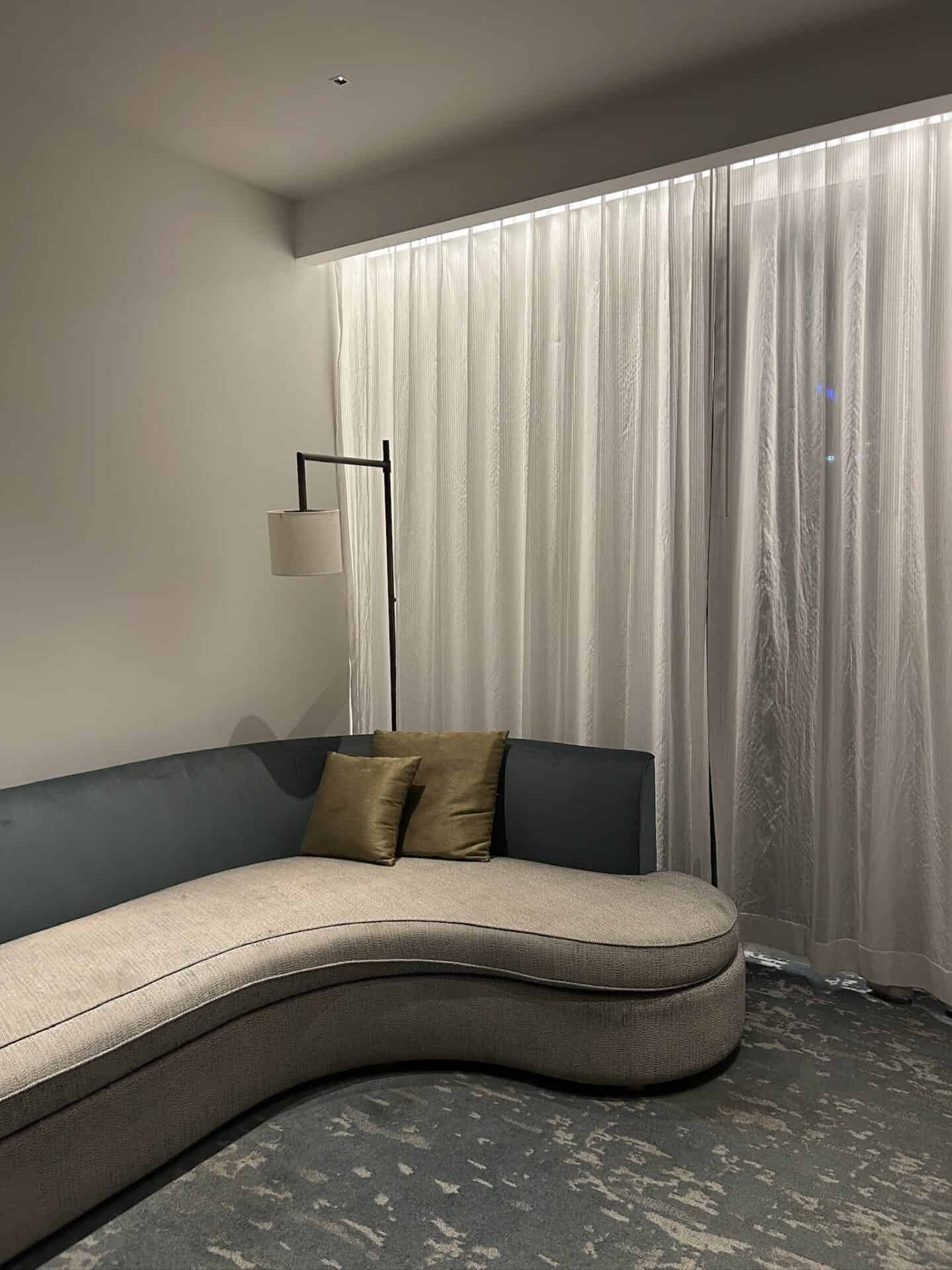 Contemporary living room with curved sofa and sheer curtains.